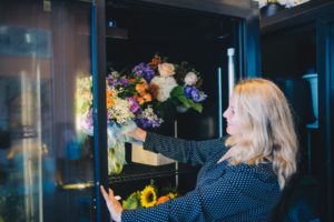 Woman adjusting flowers in large floral cooler