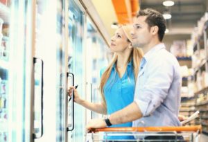 Supermarket couple in front of a freezer, purchasing frozen food