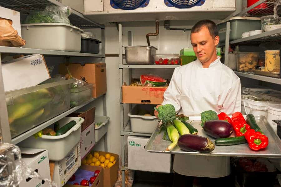 Chef in walk-in cooler looking at ingredients